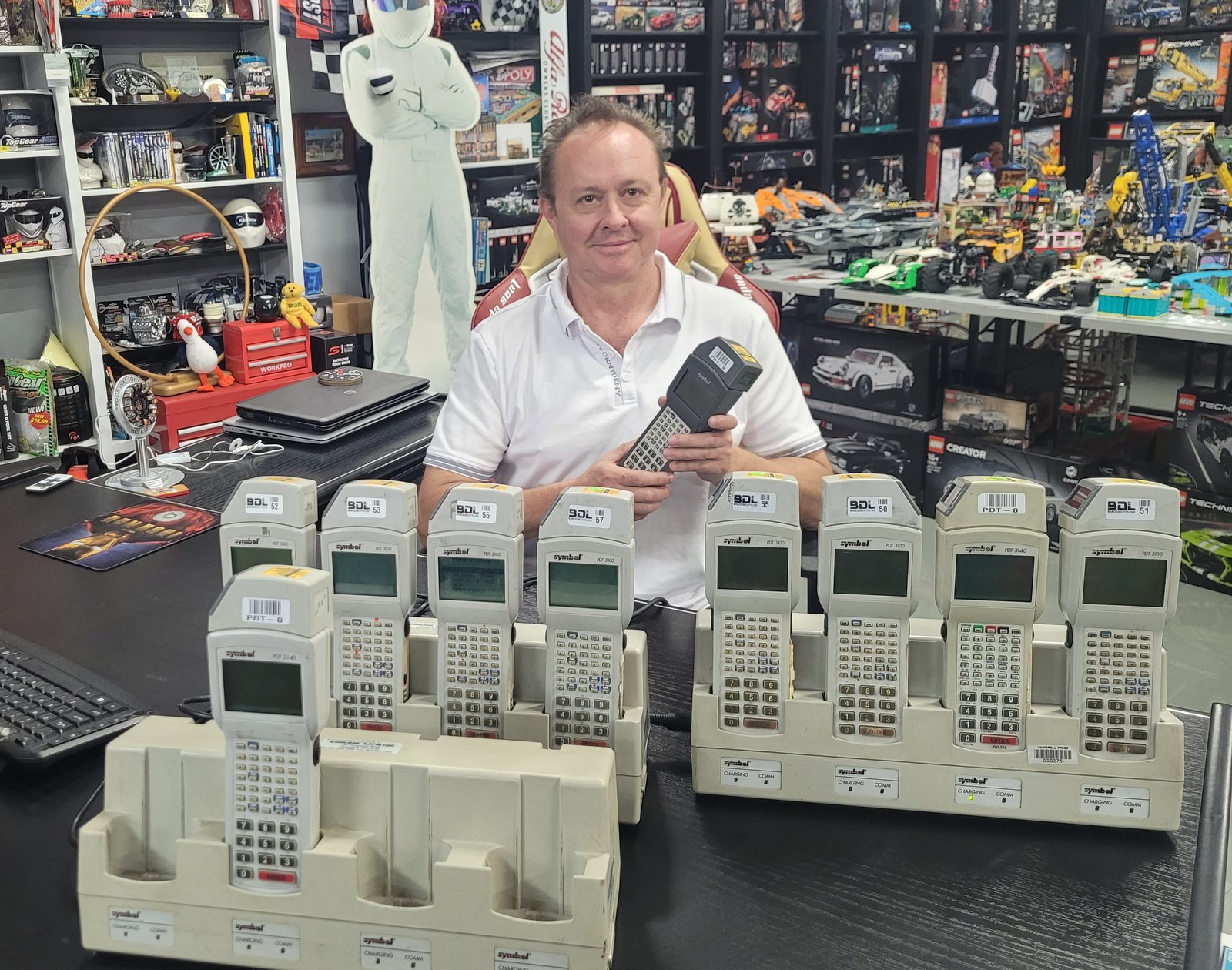 Andrei Spiegel at his desk in Berowra with ten Symbol PDT 3100 and PDT 3140
                  batch terminals standing in two charging cradles, holding an eleventh